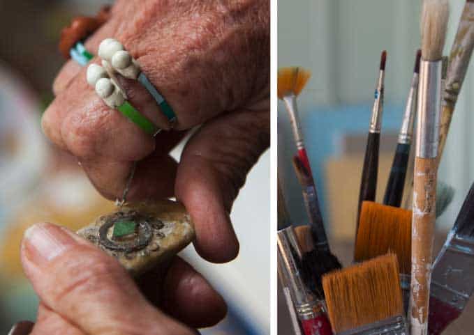 hands carving out a piece of clay, and a jug full of brushes