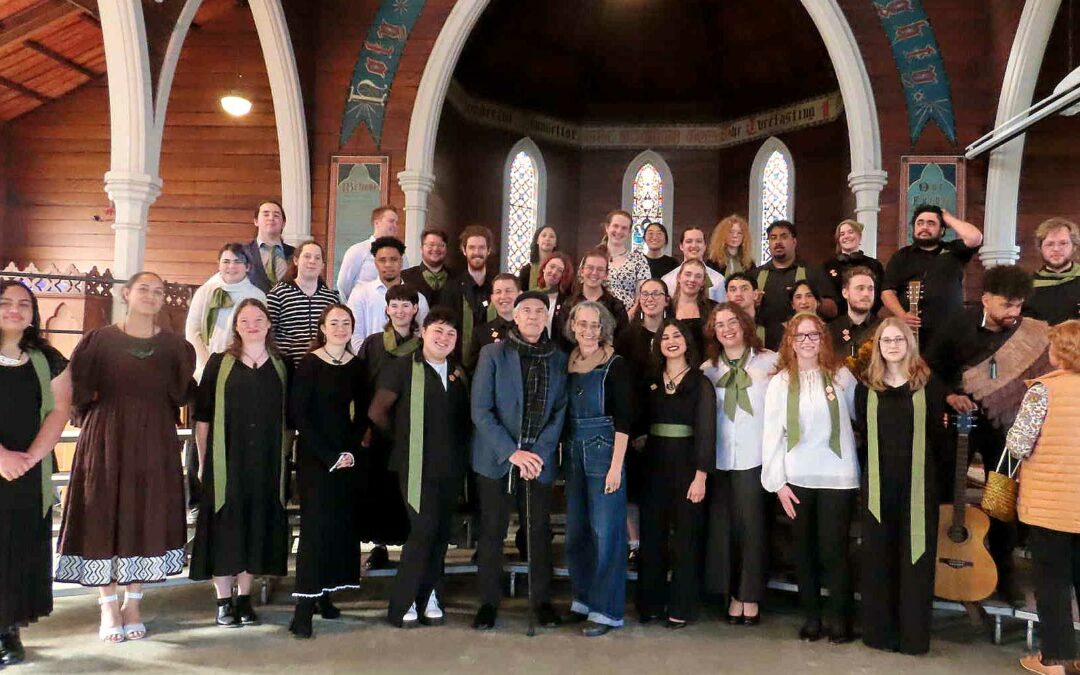 choir people standing in a church, with green scarves and some women with tarditional maori facial tattoos