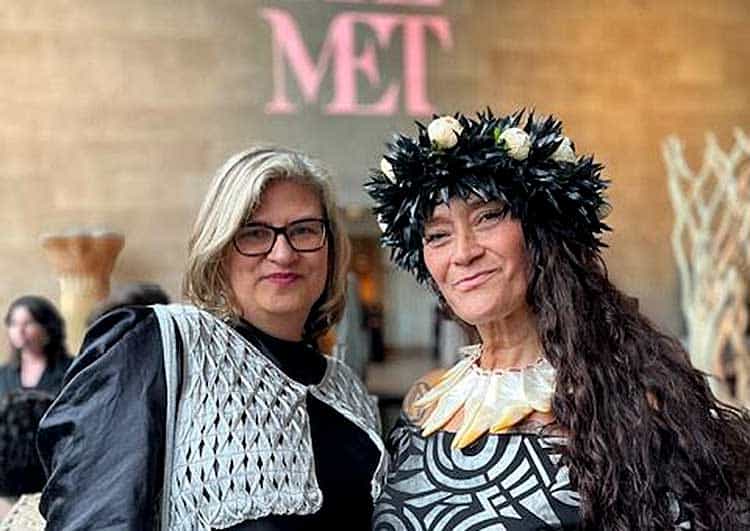 two white, mature women one with a fancy arty hat and the letters MET on wall in background