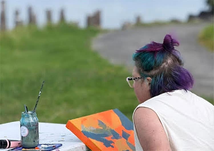 person painting in the outdoors, orange canvas