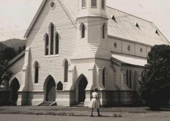 old colonial chruch with woman in dress walking toward it, 1950's black and white photo