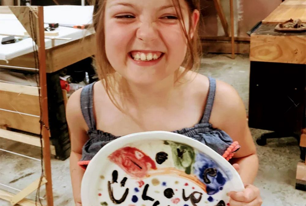 Girl smiling with self made decorated ceramic plate